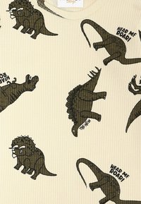 Majica s kratkimi rokavi iz rebraste kremne tkanine, ki prikazuje temne ilustracije dinozavrov in besedilo: "Slišite me rjoveti!" in "NOVO."