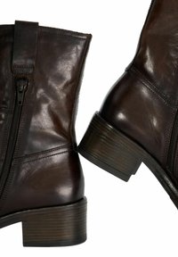 Brown leather ankle boots with a shiny finish, featuring a side zipper and a stacked wooden heel. Smooth texture and minimal stitching.