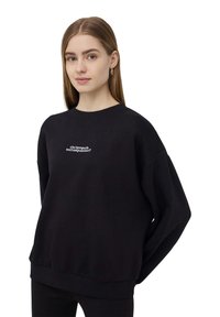 Felpa nera con scollo rotondo, vestibilità oversize e polsini a coste. Caratterizzata da testo ricamato bianco sul petto. Tessuto dalla consistenza morbida.