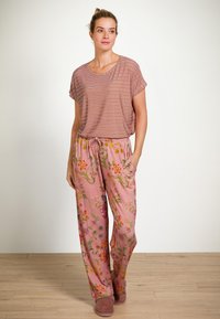 Gestreepte korte mouw top in roos en room, gecombineerd met roze geborduurde broek met bloemontwerpen en zijzakken.