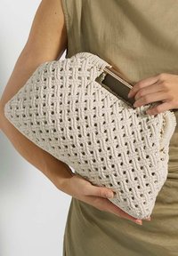 Beige woven handbag with a geometric pattern, featuring a solid structure and a soft texture. It has a wooden handle for easy carrying.