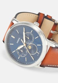 Braunes Lederarmbanduhr mit blauem Zifferblatt. Verfügt über silberne Stundenmarker, goldene Zeiger und drei Teilzifferblätter für Datum, Wochentag und Mondphase.