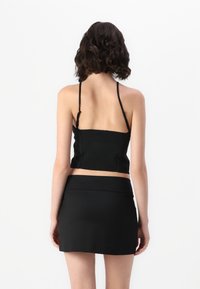 Black crop top and mini skirt set, featuring a sleek, smooth fabric, thin straps, and a fitted design with a high waistband.