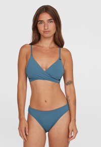 Modrý bikinový set s topom v štýle zavinovania s tenkými ramienkami a zodpovedajúcimi nízkymi nohavičkami, vyrobený z hladkej elastickej tkaniny. Bez viditeľných vzorov.