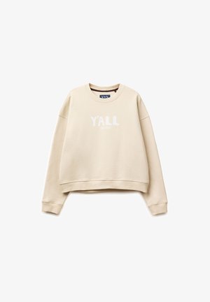 Béžová mikina s kulatým výstřihem, dlouhými rukávy a žebrovanými manžetami, s bílým nápisem "Y'ALL" vytištěným uprostřed přední strany.