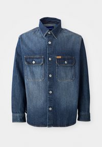 Denimskjorte i mørkeblå med knappe-ned krage, to brystlommer og HUGO-logo. Standard passform med lange ermer.