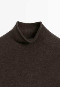 Brun polotröja gjord av mjukt tyg, med en vikbar krage och en slät, texturerad yta. Enkelt och enhetligt mönster.