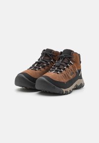 Braune Wildlederschuhe mit schwarzem Gummi zum Wandern verfügen über ein strukturiertes Obermaterial, eine verstärkte Zehenkappe, einen gepolsterten Schaft und eine profilierte Laufsohle mit multidirektionalem Grip.