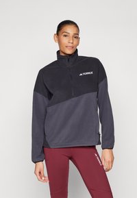 Pullover in fleece nero e grigio scuro con zip a quarti e colletto alto, caratterizzato dal logo bianco "TERREX" sul petto e polsini elasticizzati.