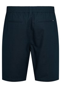 Tengerészkék rövidnadrág elasztikus derékrésszel, két hátsó álos zsebbel, és kis piros-fehér-kék zászlóval díszített jobb oldali zsebbel.