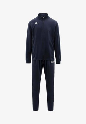 Tuta Kappa blu navy con giacca con zip integrale e pantaloni abbinati, con logo Kappa bianco sul petto e sulla coscia sinistra.
