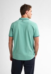 Poloko s krátkymi rukávmi v mäty zelenej farbe, s jednofarebným prevedením, golierom a modrým akcentom na okrajoch rukávov. Jednoduchý a klasický dizajn.