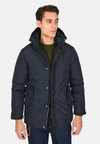 Giubbotto puffer blu navy con cappuccio removibile, due tasche frontali e chiusura con zip. Presenta dettagli con cordoncini e una texture liscia.