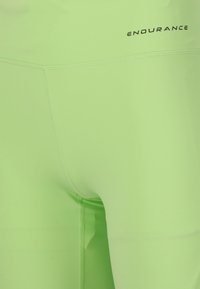 Ljusgröna sportleggar gjorda av stretchy material, med platta sömmar och en logotyp "ENDURANCE" nära midjan.