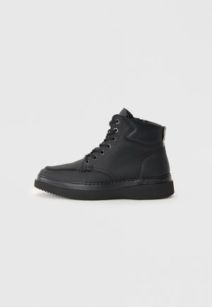 Zwarte high-top sneakers van gestructureerd leer, met een ronde neus, vetersluiting aan de voorkant, metalen ogen en een dikke rubberen zool.