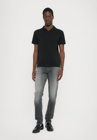 Fekete, rövid ujjú polo póló, szürke, slim fit farmernadrág és fekete mokaszinok. Simaság, klasszikus dizájn és testhez álló sziluett.