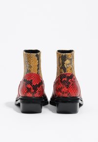 Stivaletti alla caviglia in pelle di serpente con una combinazione di colori rosso e giallo, punta quadrata e tacco a blocco nero, dal finish in pelle testurizzata.