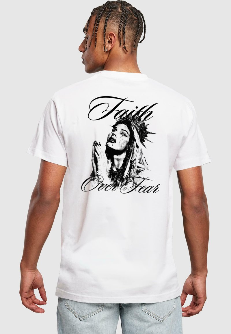 White short-sleeve t-shirt featuring a black graphic of a woman with a crown, praying, alongside the text "Faith Over Fear" in cursive.