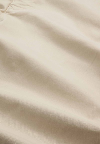 Beige Baumwollstoff mit glatter Textur, der feine diagonale Rillen und einen leichten Glanz aufweist, geeignet für die Bekleidungsherstellung.