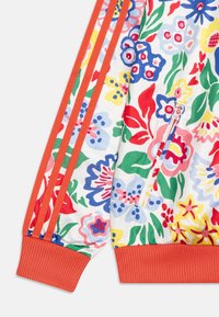 Mönstrad sweatshirt med blommor i livliga röda, blå, gula och gröna färger. Inkluderar orange ribbade ärmslut och axelränder.