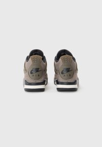 Baskets Nike Air en gris avec des accents noirs. Présentent un col rembourré, une finition texturée et un logo au niveau du talon. Semelle intercalaire blanche et semelle extérieure noire.
