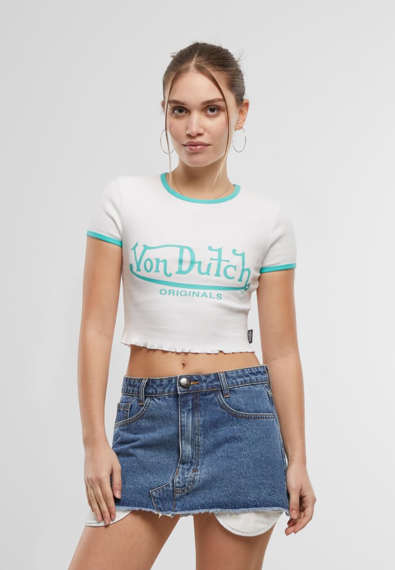 T-shirt blanc coupé avec des accents turquoise et graphique "Von Dutch Originals" ; associé à une mini jupe en denim bleu avec un ourlet effiloché.