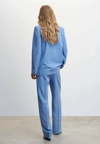 Lichtblauw pak bestaande uit een op maat gemaakt colbert en rechte broek, met een gladde textuur en minimalistisch ontwerp.