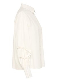 Camicia bianca a maniche lunghe in cotone con colletto classico, caratterizzata da maniche arricciate con dettagli in nastro e polsini con bottone. Silhouette dritta.