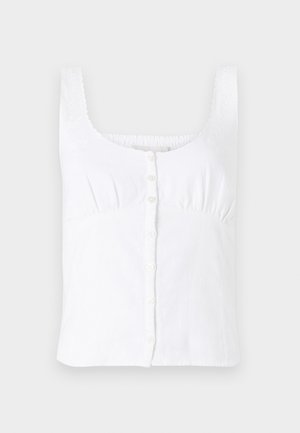 Balta lininė be rankovių palaidinė su apvaliomis iškirptėmis, priekyje su sagų uždarymu ir subtiliais siuvinėjimais ant petnešėlių. Lygus sluoksnis.