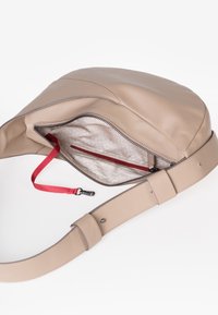 Borsa a tracolla in pelle beige con ampia tracolla regolabile, cerniera aperta che rivela un interno in tessuto chiaro con motivo e clip per chiavi rossa.