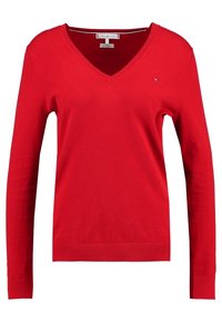 Pull-over rouge en V, fabriqué en coton, avec des manches longues et un design ajusté. Petite accent logo dans le coin supérieur gauche.
