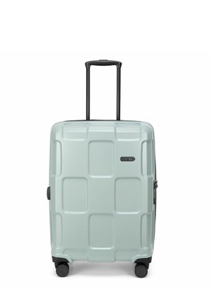 Valise rigide bleu clair avec quatre roues, poignée noire rétractable et motif carré texturé sur la surface avant.