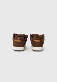 Brown suede sneakers featuring a padded collar, mesh tongue, and white rubber sole with branding on the heel and side.
