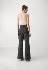 Strapless crèmekleurig top met een gestructureerde stof en een lichte rug, gecombineerd met zwart-witte tweed wijde broek.