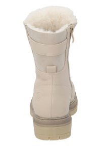 Bottine beige avec doublure en fausse fourrure, extérieur en cuir lisse, fermeture éclair sur le côté et semelle en caoutchouc texturé.