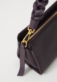 Borse a tracolla in pelle viola con tracolla intrecciata e accessori in oro, dotata di chiusura con zip e texture liscia.