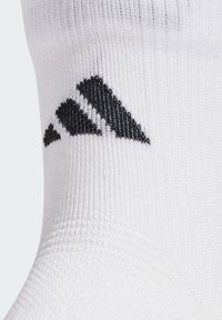 White athletic sock with textured fabric featuring a black three-stripe logo. Sock design includes a ribbed cuff for comfort and fit.