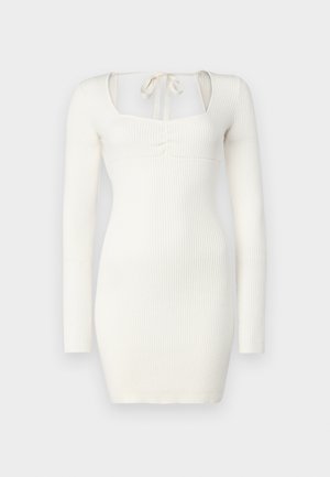 Fehér, bordázott, hosszú ujjú ruha négyzet alakú nyakkivágással, elöl csomózott részlettel és testhezálló fazonnal.