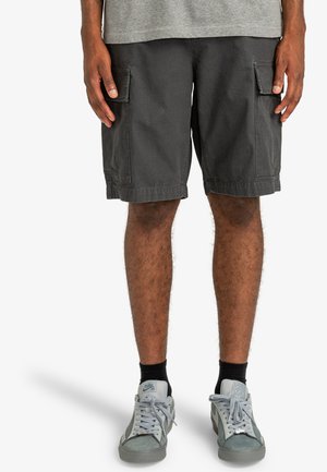 Gray cargo shorts made of durable fabric, featuring two side pockets, a straight cut, and a cuffed hem. Paired with gray sneakers.