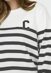 Camisa de manga larga blanca con rayas grises horizontales. Presenta una letra "C" bordada en negro en la parte izquierda del pecho. Material de algodón suave.