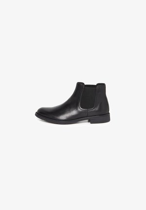 Botte Chelsea en cuir noir avec panneau latéral élastique et petit talon, présentée en profil latéral sur fond blanc.