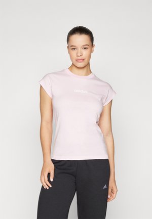 T-shirt en coton rose pâle avec des manches courtes roulées et un logo "adidas" blanc à l'avant, associé à un pantalon noir.