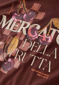 Maroon fabric with a design of cherries and text reading "Mercato della Frutta" in white, featuring pink and beige elements and a textured background.