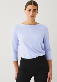 Lichtblauwe lange mouw top met een ronde hals, een gladde textuur en een losse pasvorm, gecombineerd met hoge taille zwarte broek.