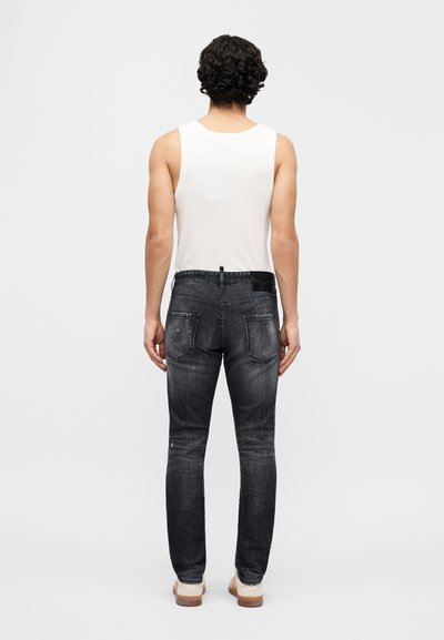 Μαύρο τζιν με στενή εφαρμογή, με μέτριο ύψος στη μέση, σχέδιο με πέντε τσέπες και διακριτικές φθορές. Φοράται με λευκό αμάνικο τοπ.