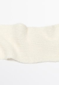 Striscia di tessuto lavorato a maglia morbido e bianco sporco con una trama a coste, mostrata piatta su uno sfondo bianco uniforme.