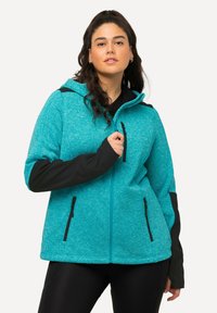 Giacca a zip turchese con dettagli neri, realizzata in materiale texturizzato. Presenta un cappuccio, tasche laterali e maniche a contrasto.