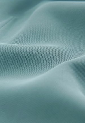 Gaiši zils teksturēts audums ar gludu virsmu un rievotu rakstu, kas demonstrē locījumus un maigas viļņus materiālā.