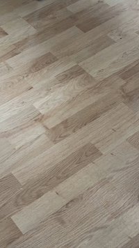 Laminat podovi od svijetlog hrasta s različitim nijansama smeđe i krem boje. Sadrže teksturu drvenih godova i pravokutne daske raspoređene u pomaknutom uzorku.