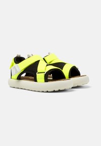 Neon gula och svarta sandaler med breda tygremmar, korkfotbädd och vit gummisula. Justerbara stängningar för en bra passform.